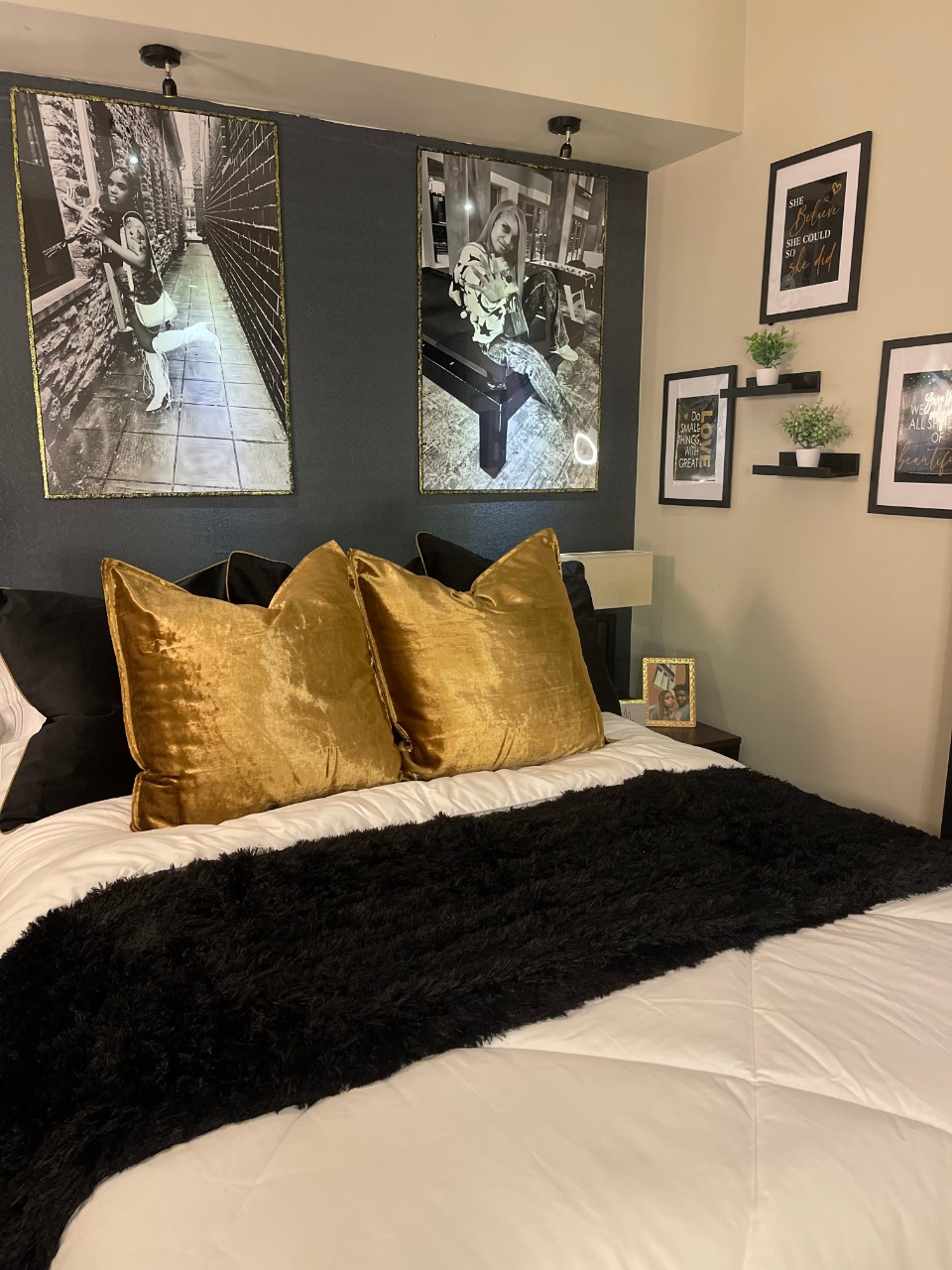 Bed with black and gold linens and photographs on the walls